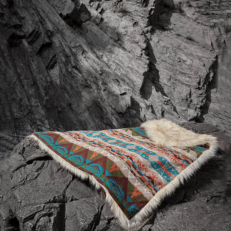 Anifurry turquoise rain dance faux fur blanket laid on the black rocks.