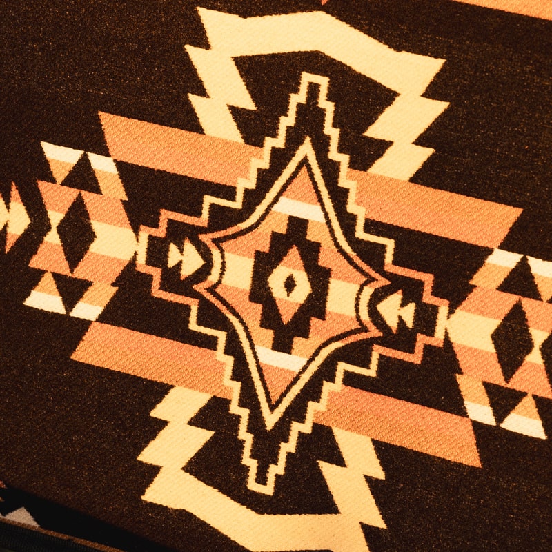 Southwest-style woven throw blanket with intricate geometric patterns in orange, white, and brown.
