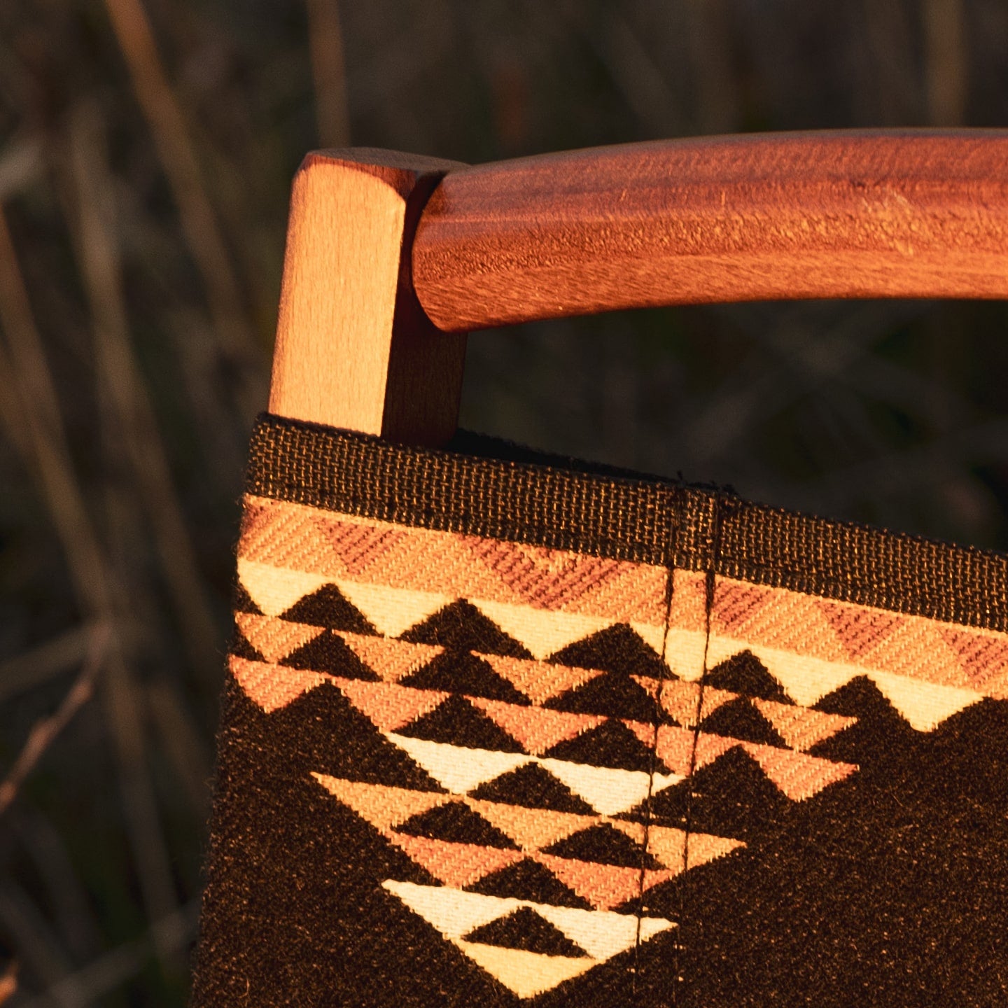 Dark brown wood frame folding chair with black base and orange geometric patterned fabric.