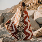 Woman wrapped in a blanket standing on rocky coast.