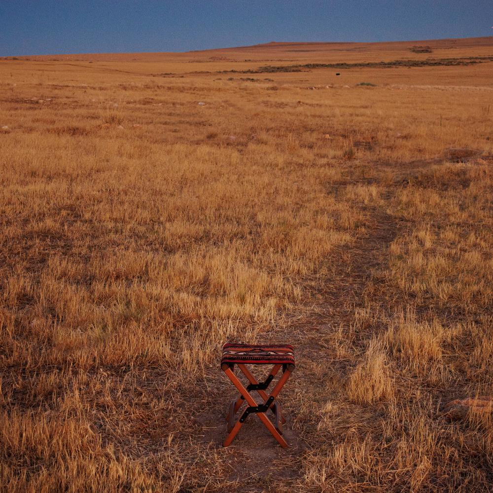 Anifurry Wood outdoor stool Sierra in a vast, open field with dry grass under a clear blue sky