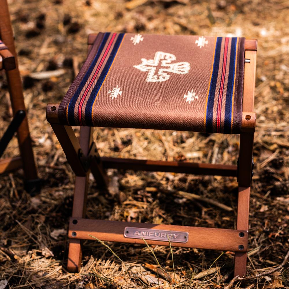 Anifurry wood outdoor stool with a patterned thunderbird on a natural ground surface