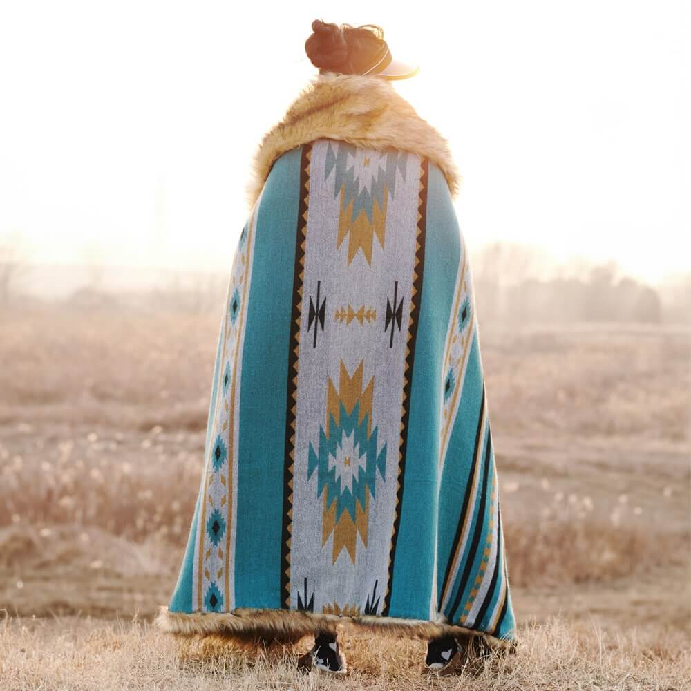 A person covered in a classic Aztec Faux Fur Throw Blanket in the sun.