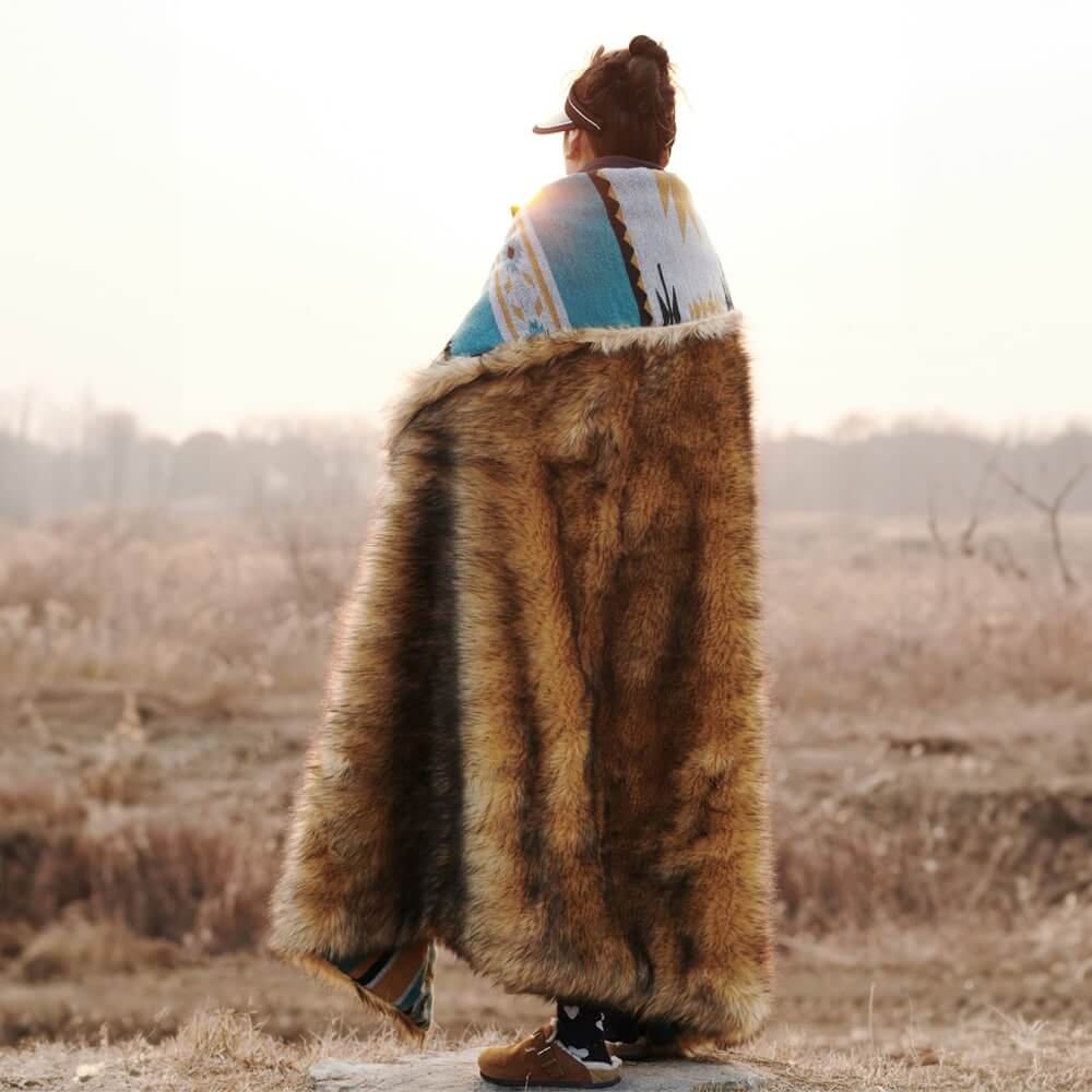 A person covered in a classic Reversible Aztec Faux Fur Throw Blanket in the sun.