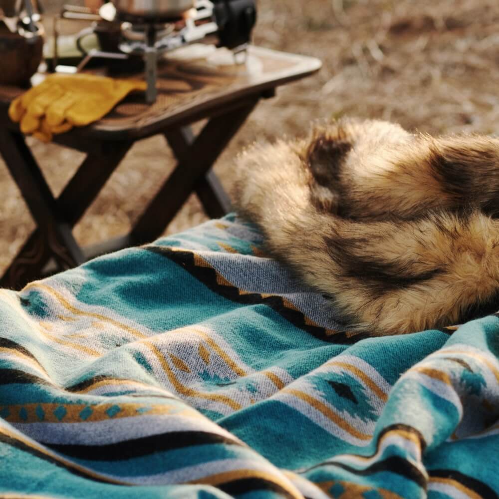 A high-end Aztec faux fur throw blanket and a small wooden table.