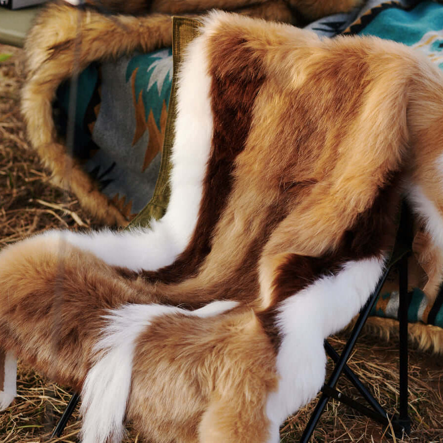 A chair covered by a high-end Faux Impala Pelt Rug, and an Aztec Faux Fur Blanket in the background.