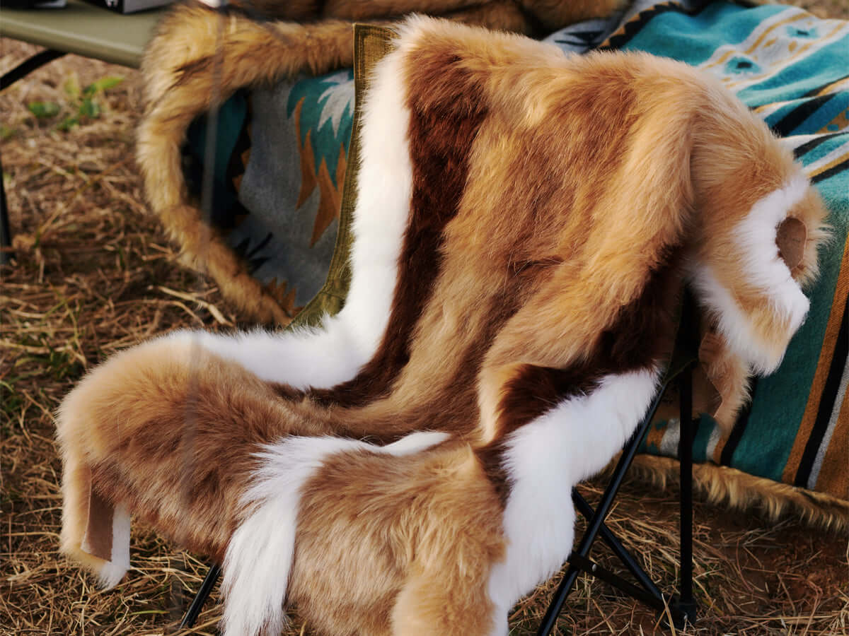 A chair covered by a high-end Faux Impala Pelt Rug, and an Aztec Faux Fur Blanket in the background.