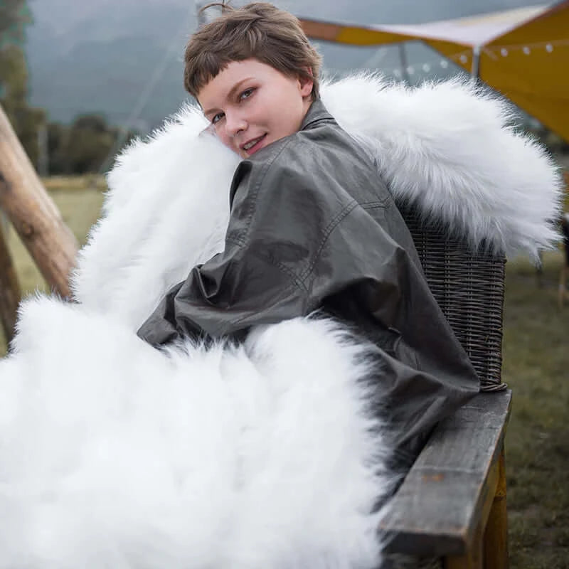 The model wearing a queen size fluffy white faux fur blanket. The blanket is easy to wash. Beautiful decoration for home.