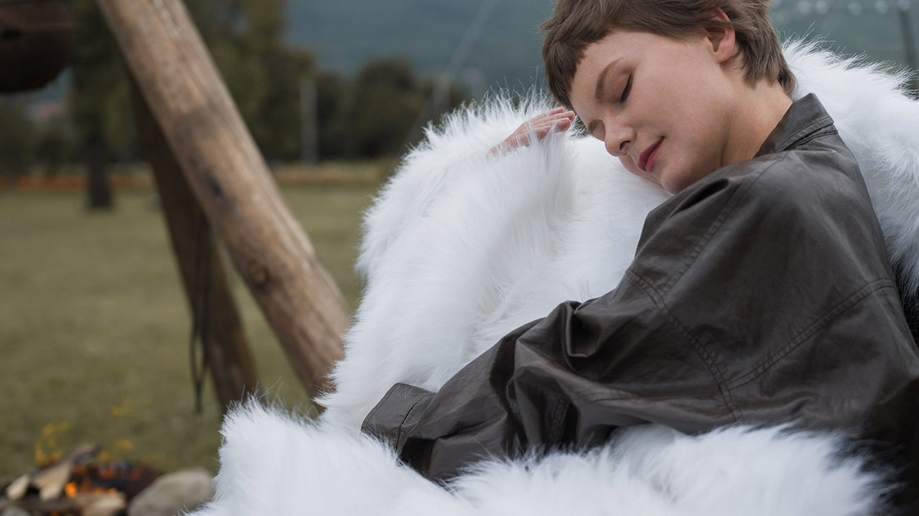 The model wearing a queen size fluffy white faux fur blanket. The blanket is easy to wash. Beautiful decoration for home.