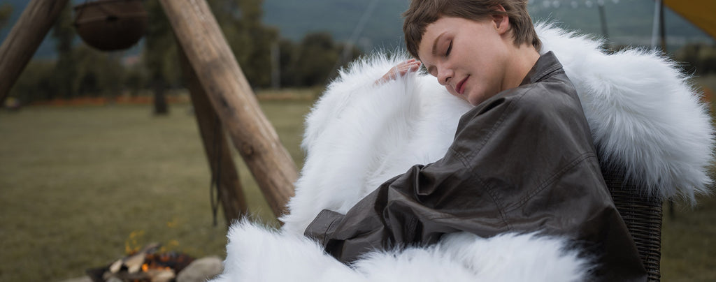 The model wearing a queen size fluffy white faux fur blanket. The blanket is easy to wash. Beautiful decoration for home.