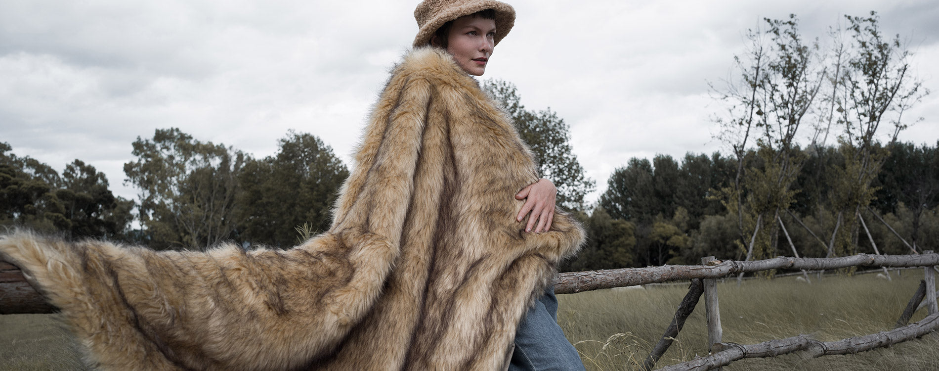 The model wearing a plush and warm golden faux fur blanket. The blanket is multi-functional and easy to wash.