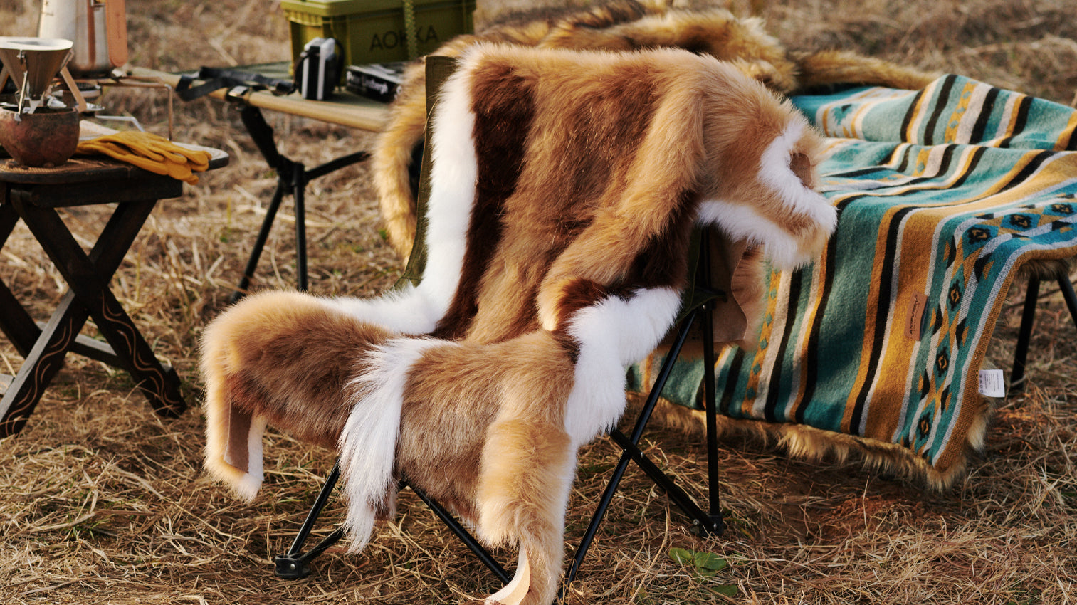 A chair covered by a Faux Impala Pelt Rug, surrounded by Aztec Faux Fur Blanket and wooden tables.
