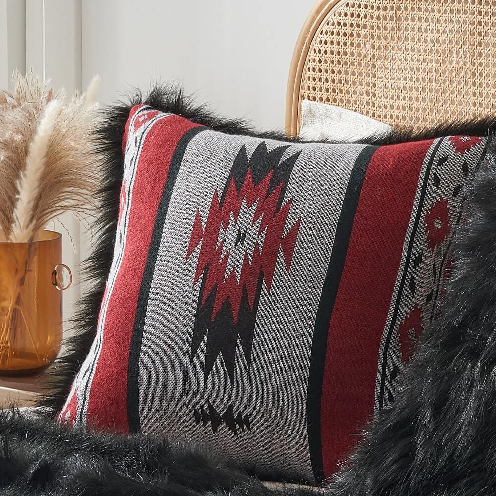 The red aztec pattern on one side and luxurious black faux fur on the other pillow covers on the bed.