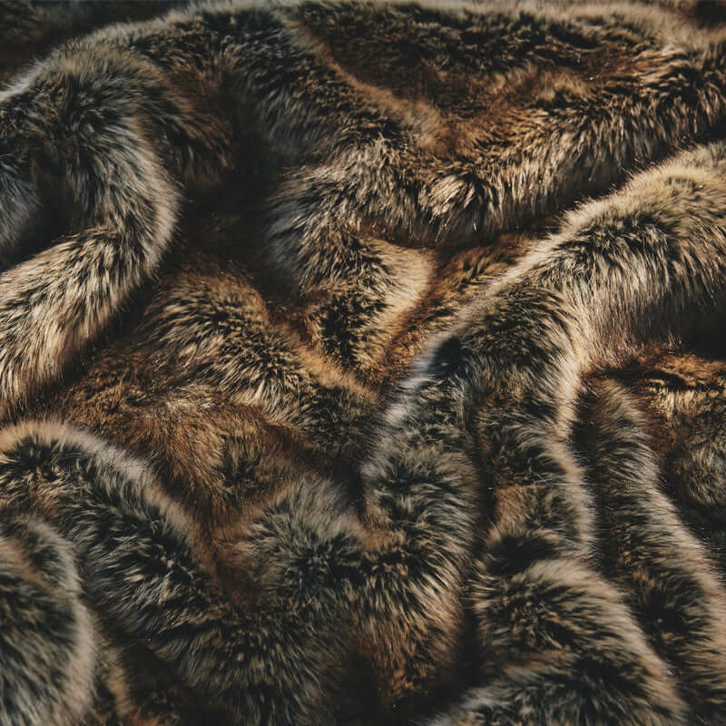 The glossy brown rug with luxurious faux fur is on the ground. It has one fluffy side and one non-slip reverse side.