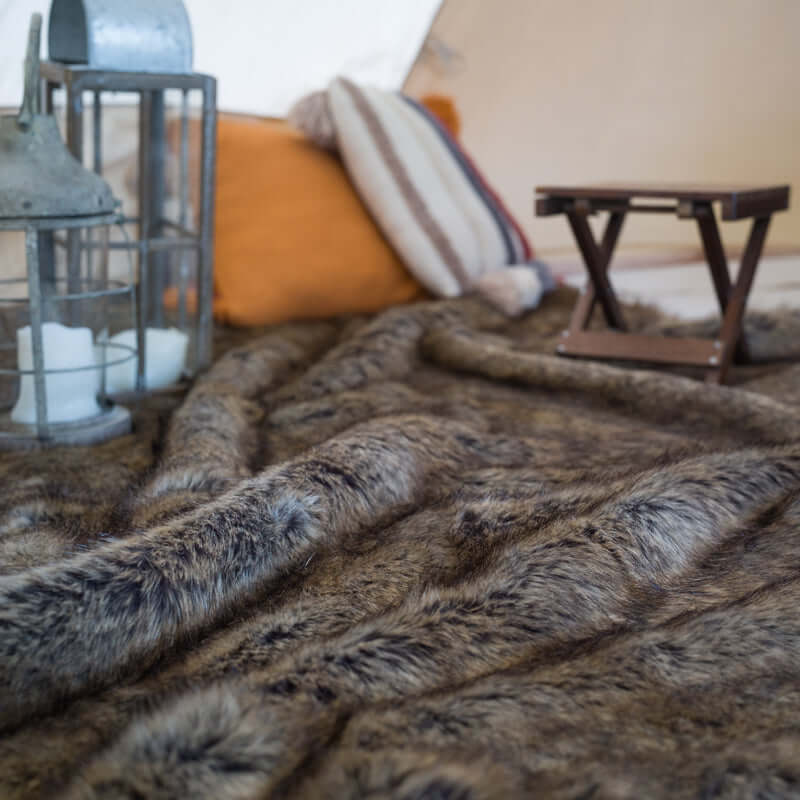 The rich-textured brown faux fur rug is next to a chair and a pillow.