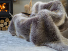 The grey faux fur rug is on a chair. The high-quality rug is reversible and suitable for home decor. Easy to wash and store.