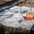 The white fake fur rug is on the ground. Great for home decoration and camping. The non-slip reverse side is practical.