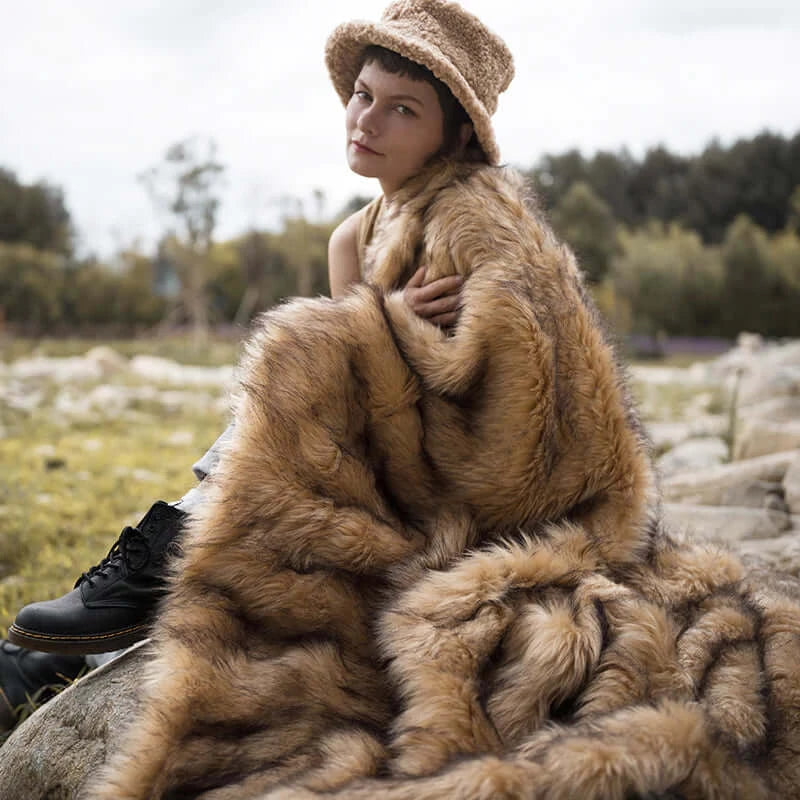 The model wearing a plush and warm golden faux fur blanket. The blanket is multi-functional and easy to wash.